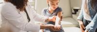 Young girl has elbow examined by orthopedic specialist while mother watches.
